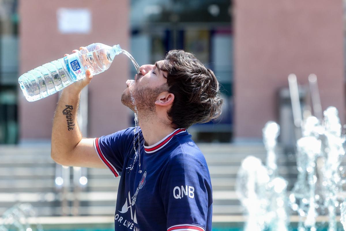Un joven bebe agua para combatir la segunda ola de calor del verano, a mediados de julio, en Madrid.