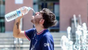 Un joven bebe agua para combatir la segunda ola de calor del verano, a mediados de julio, en Madrid.