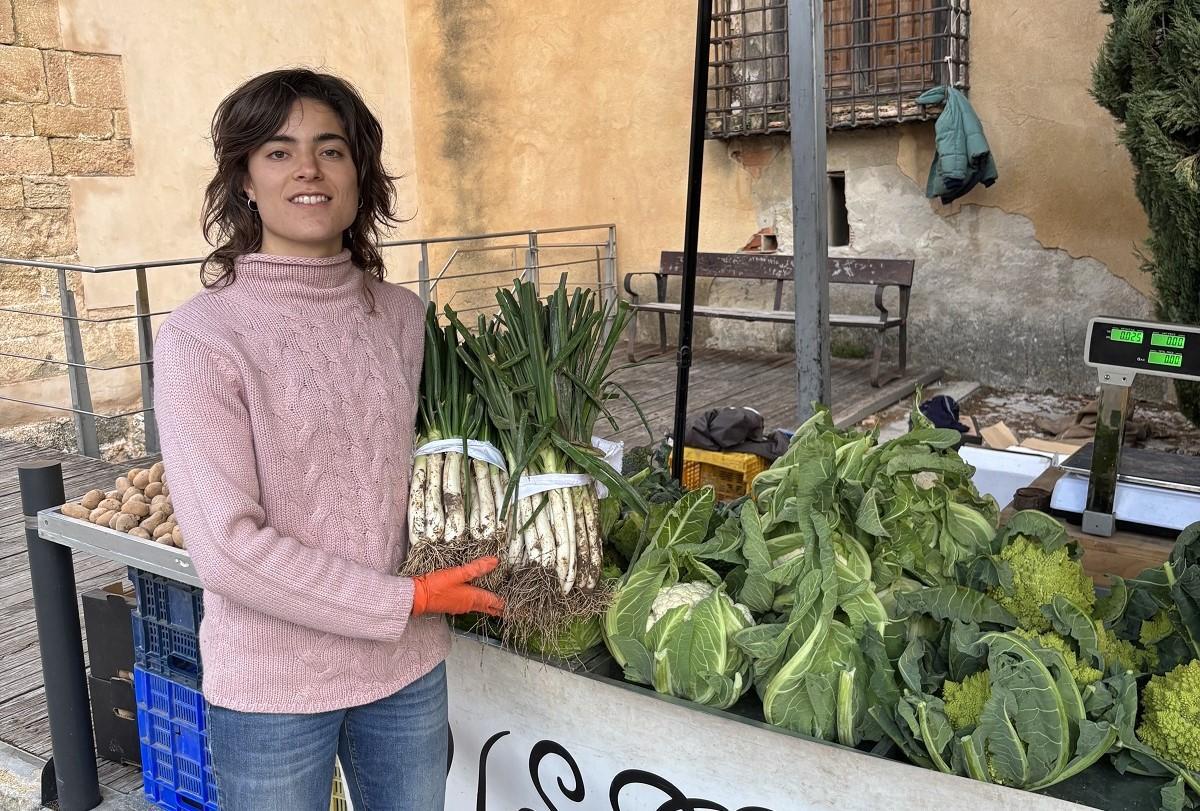 Marina Brotons, arriba, en el puesto del mercado de Cocentaina donde vende sus ‘calçots’ y otras hortalizas los jueves y sábados
