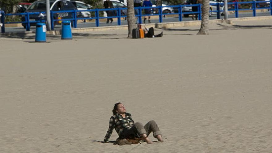 Una mujer toma el sol esta mañana en el Postiguet