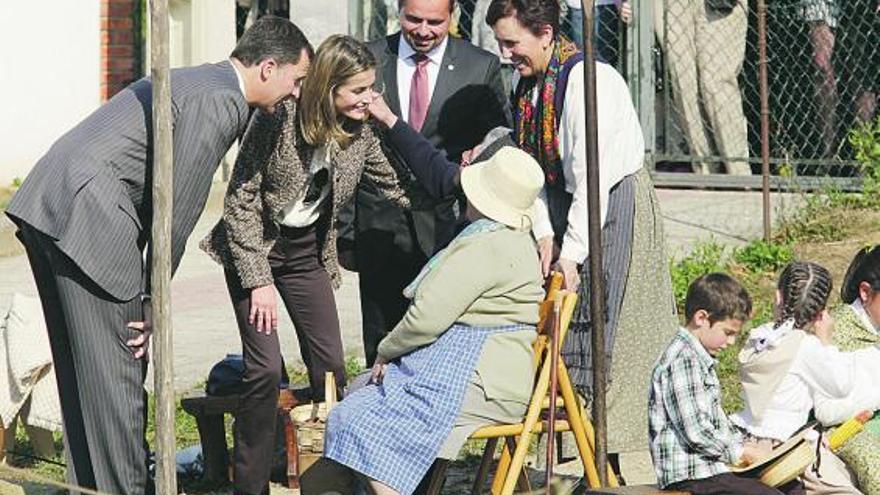 Los Príncipes saludan a Sabina Martínez y María Presentación Acebal, sentadas, durante la demostración del esfoyón del maíz.