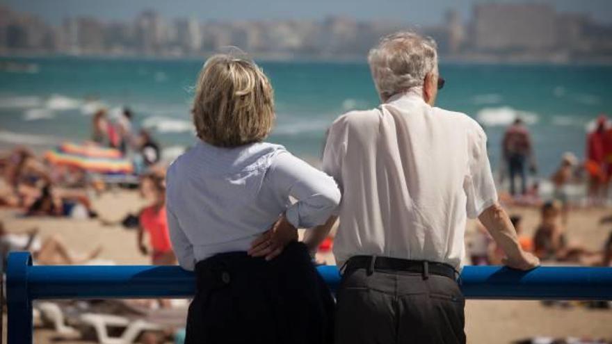 Una pareja contempla el mar y la playa llena por las buenas temperaturas durante esta semana en Alicante.