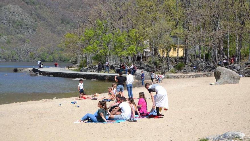 Un grupo de personas disfruta del buen tiempo, en la mañana de ayer, en una de las playas del Lago de Sanabria.