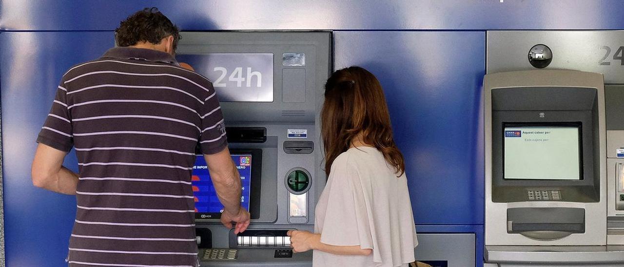 Dos clientes realizan una operación bancaria a través de una tarjeta en un cajero de una entidad financiera en una imagen de archivo.