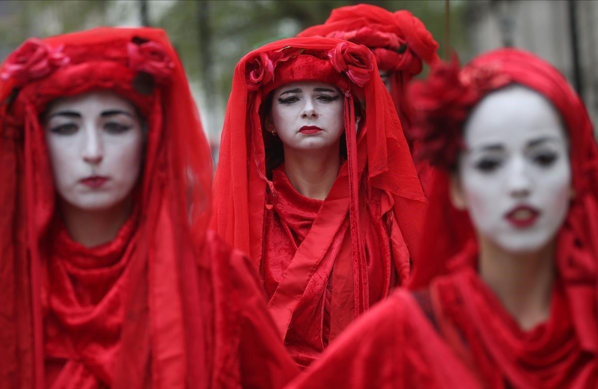 Activistas del cambio climático, vestidas de rojo, protestan cerca del Parlamento en el centro de Londres.