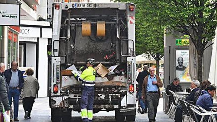 Un operario recoge basura en un camión en una calle de la ciudad.