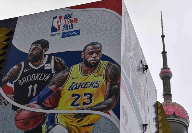 Un trabajador retira una pancarta promocional de un edificio para el partido de pretemporada de la Asociación Nacional de Baloncesto (NBA) el 10 de octubre en China entre los Brooklyn Nets y Los Angeles Lakers en Shanghai.