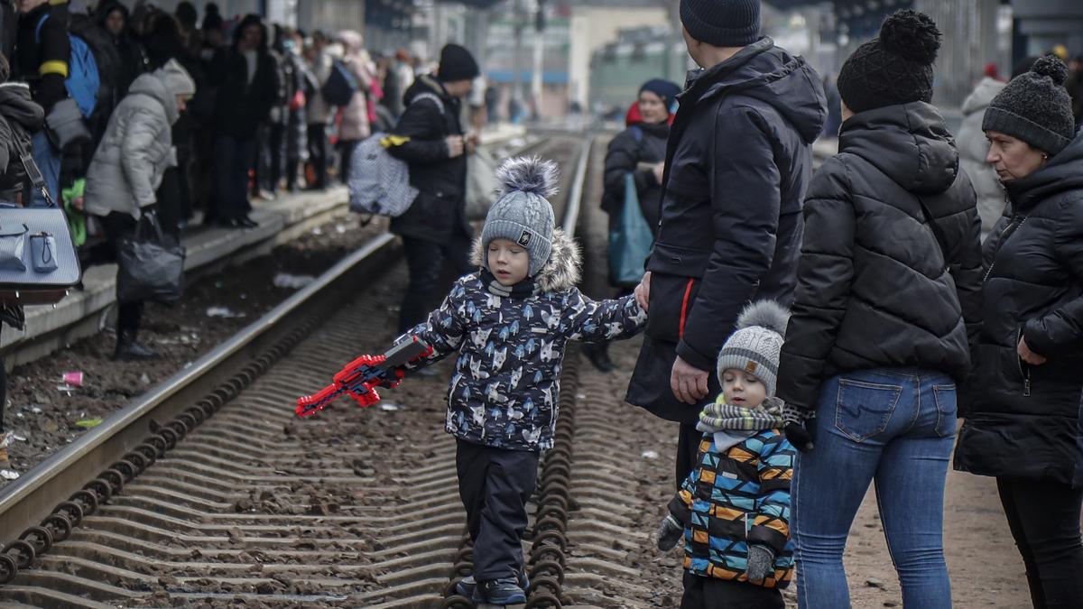 Un niño juega en las vías del tren mientras la gente se reúne en la estación principal de tren mientras intentan huir de Kiev (Kyiv)