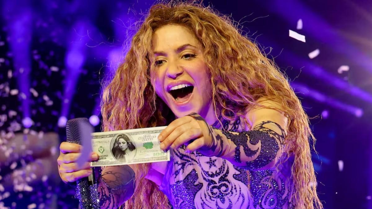 Shakira en un concierto mostrando un dólar con su foto.
