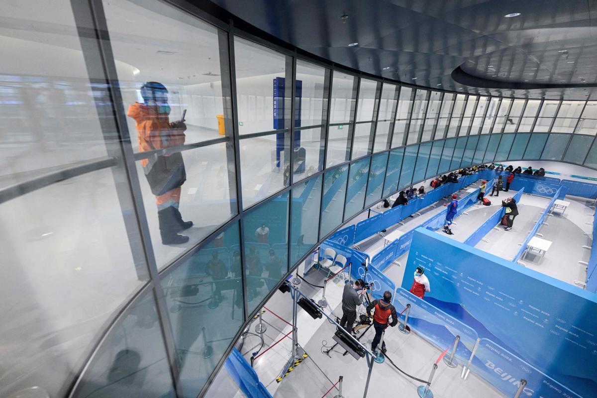 Un hombre toma fotos, mientras algunos deportistas contestan las preguntas de la prensa en las instalaciones de patinaje de los Juegos Olímpicos de Invierno de Pekín.