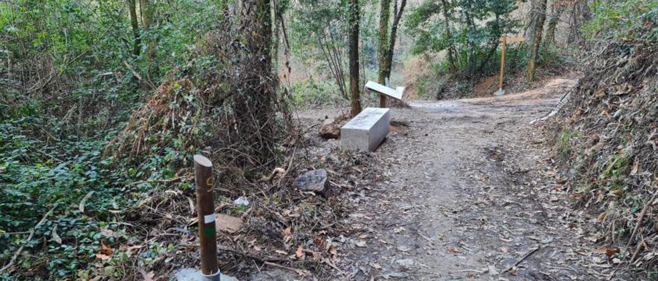 Un tramo del sendero, con un banco y un panel, con el desvío hacia O Canudo al fondo.