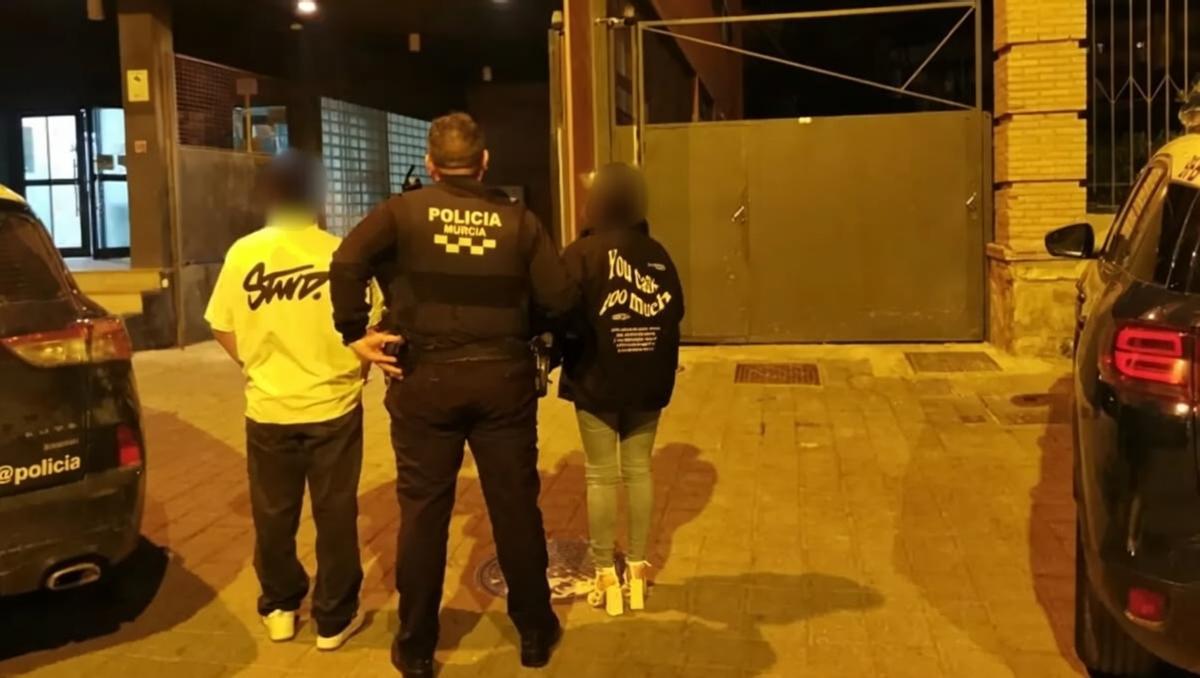Un agente de la Policía Local de Murcia custodia a los padres del niño en la puerta de Comisaría.