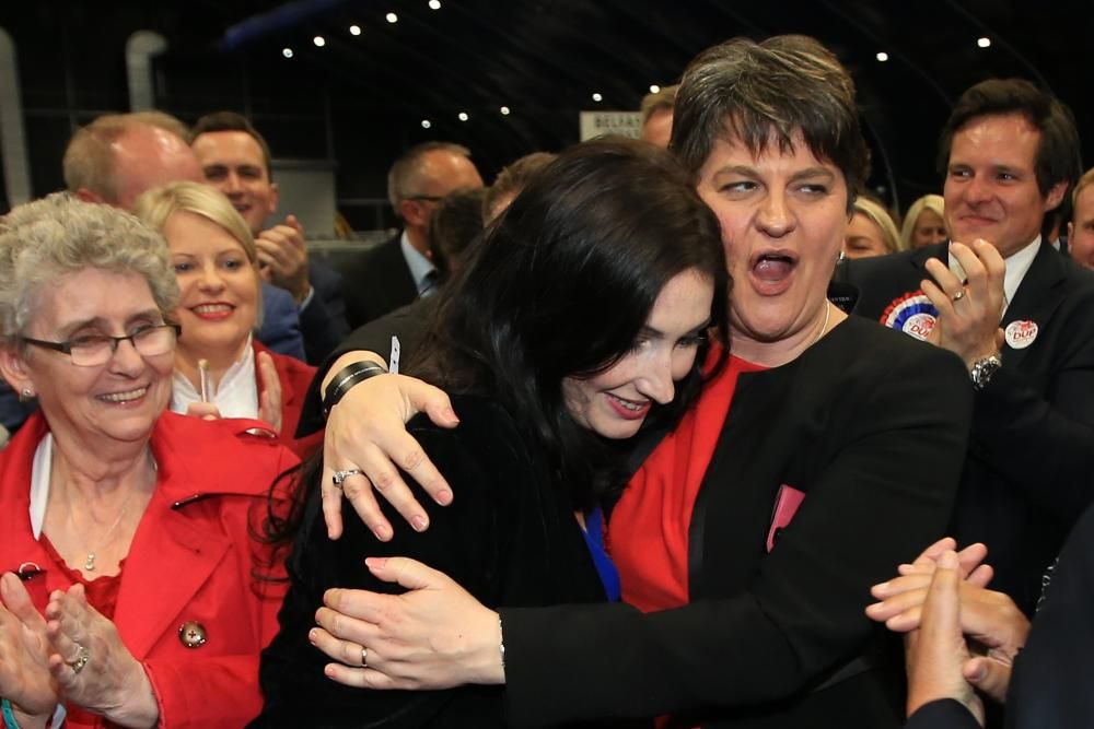 La nueva portavoz de Partido Unionista Democrático (DUP), Emma Little Pengelly (C), recibe un abrazo de la líder del partido DUP, Arlene Foster (d), luego de ganar el asiento en el sur de Belfast del SDL.