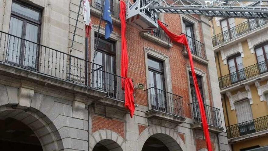 Los bomberos colocan el lazo rojo en el Ayuntamiento.