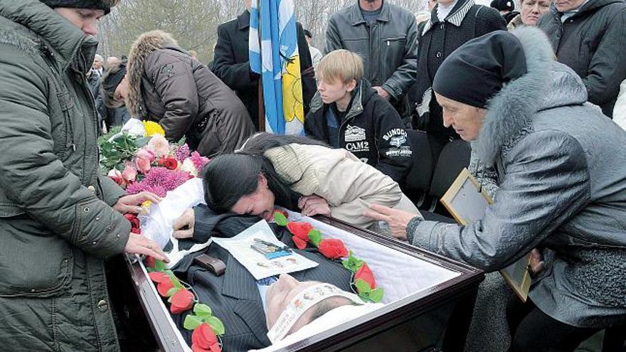 Una mujer llora sobre el féretro de un familiar durante el funeral por las víctimas del &quot;Nerpa&quot;.