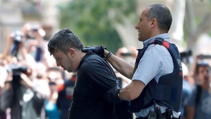 Un mosso introduce al detenido por el asesinato de una menor en Vilanova en su domicilio para proceder al registro de la vivienda.