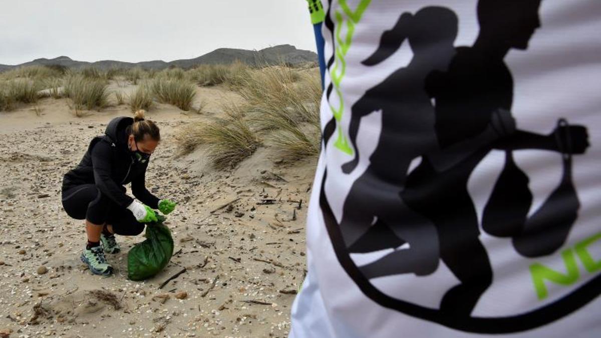 Una joven recoge residuos en una playa de Almería.