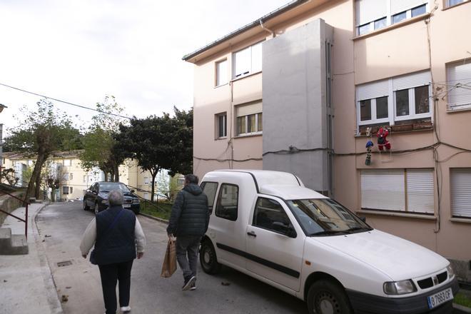 Una pareja camina por la calle de La Carriona donde está la vivienda en la que fue hallada muerta Soraya Suárez, a la derecha.