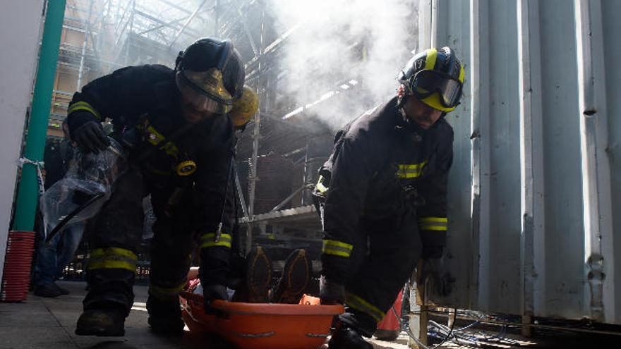 Dos bomberos sacan al desgraciado víctima de un ficticio soponcio como consecuencia de un cortocircuito de mentirijillas, ayer, en Santa Catalina.