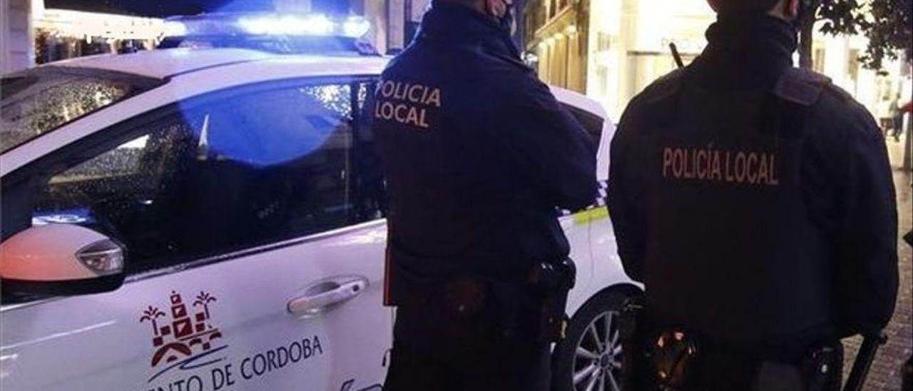 Dos agentes de la Policía Local junto a un vehículo policial.