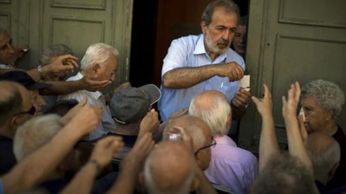 Un grupo de pensionistas se agolpa ante un banco ateniense.