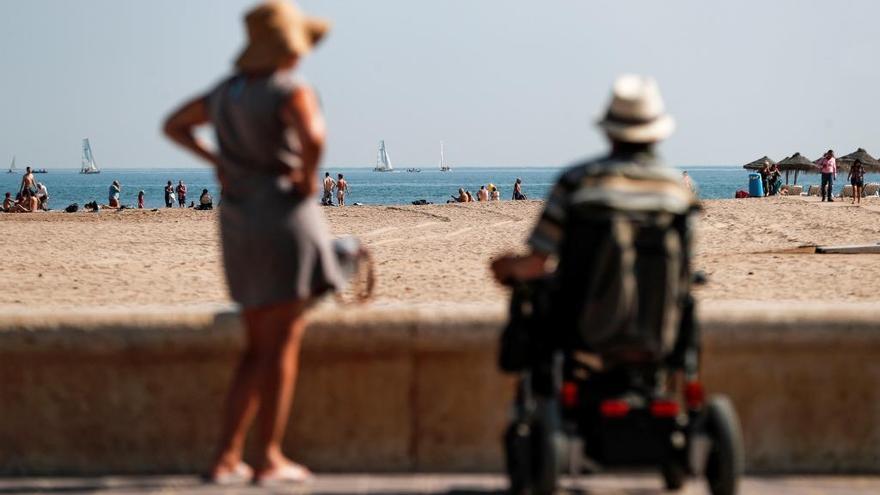 Varias personas toman el sol en la playa.