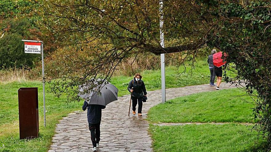 Caminantes en la senda costera de Gijón, cerca de la playa de Peñarrubia, ayer. | Juan Plaza