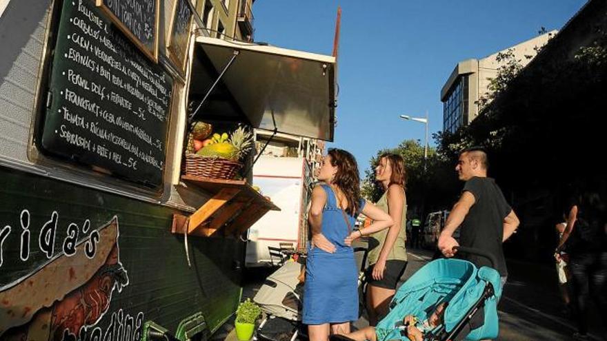 Una família s&#039;interessa pels productes que ofereix una de les caravanes de la Muralla Street Food