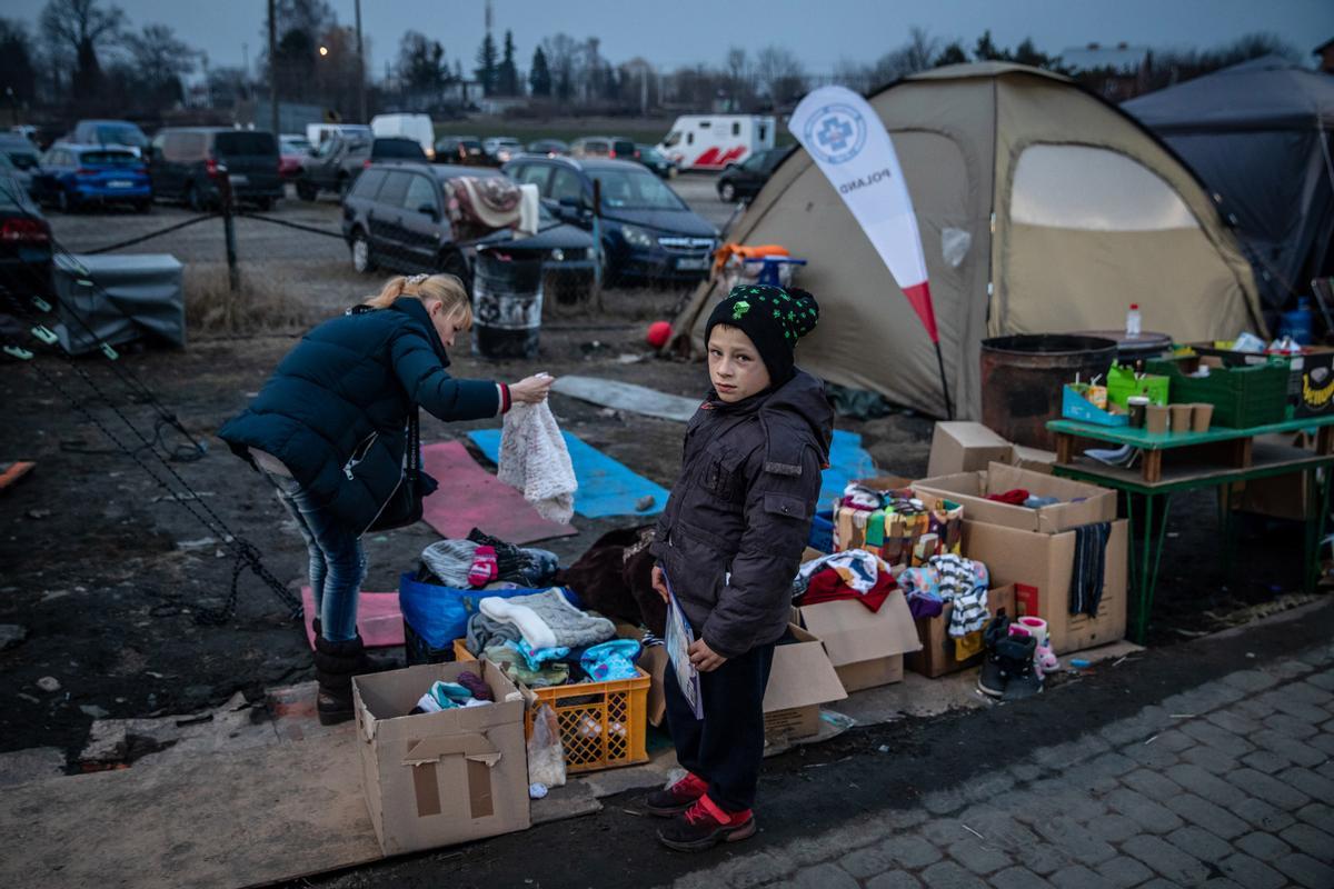 Una refugiada procedente de Ucrania y su hijo recogen prendas de ropa de un punto de ayuda instalado en la frontera, en Medyka, Polonia.
