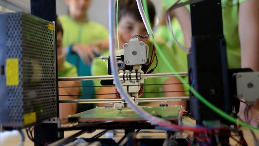 Varios alumnos participan en un taller con una impresora 3D.