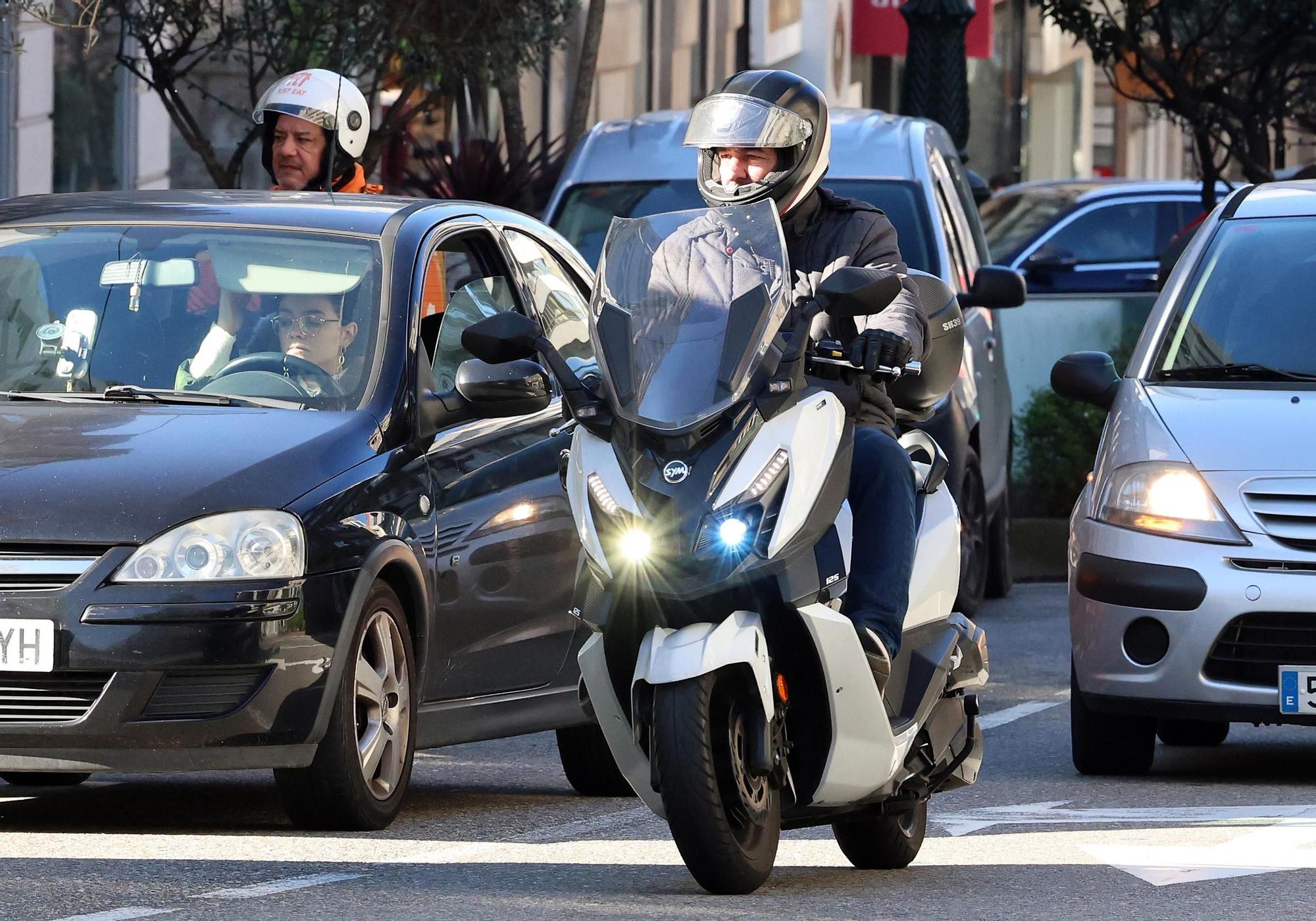 Dos motoristas circulan por el centro de Vigo con turismos a su lado