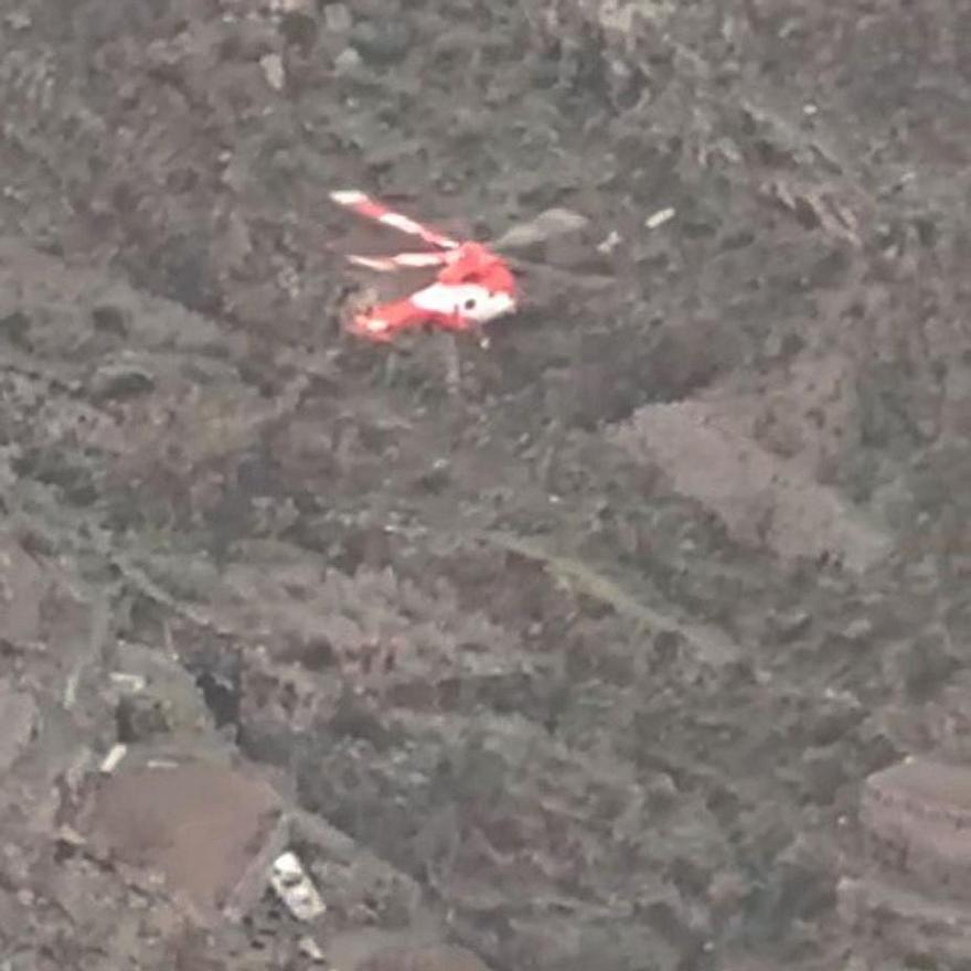 Un helicóptero sobrevuela el lugar del accidente, con el vehículo siniestrado abajo.
