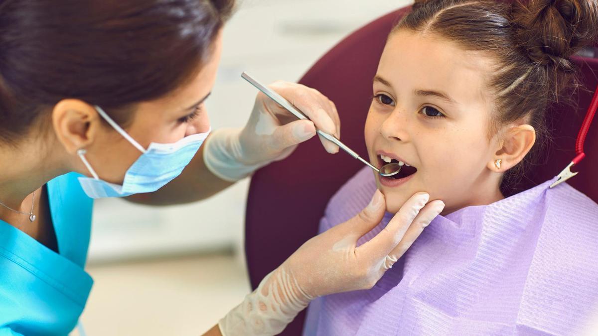 Una dentista examina la boca de una niña.