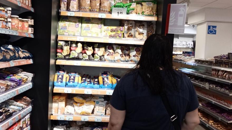 Mujer mirando la sección de productos sin gluten en el supermercado.
