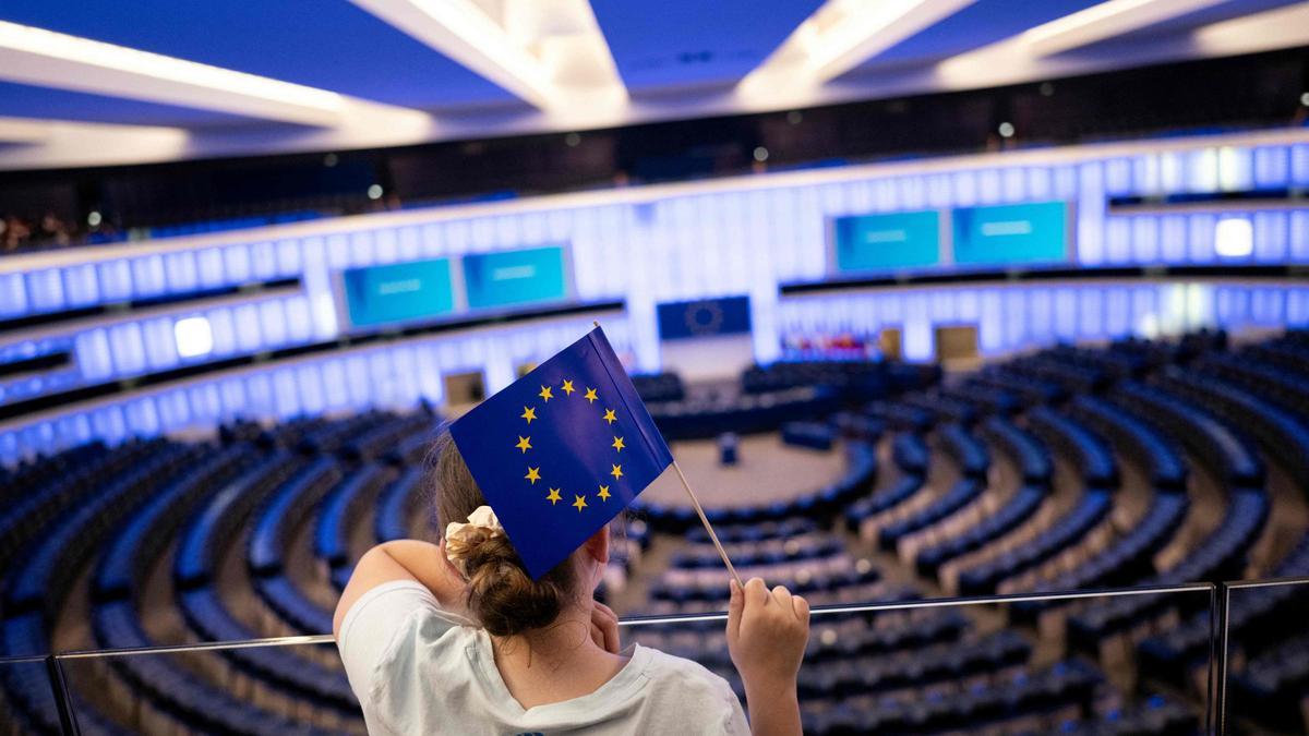 Una niña con una bandera de la UE observa el hemiciclo del Parlamento Europeo en Estrasburgo.