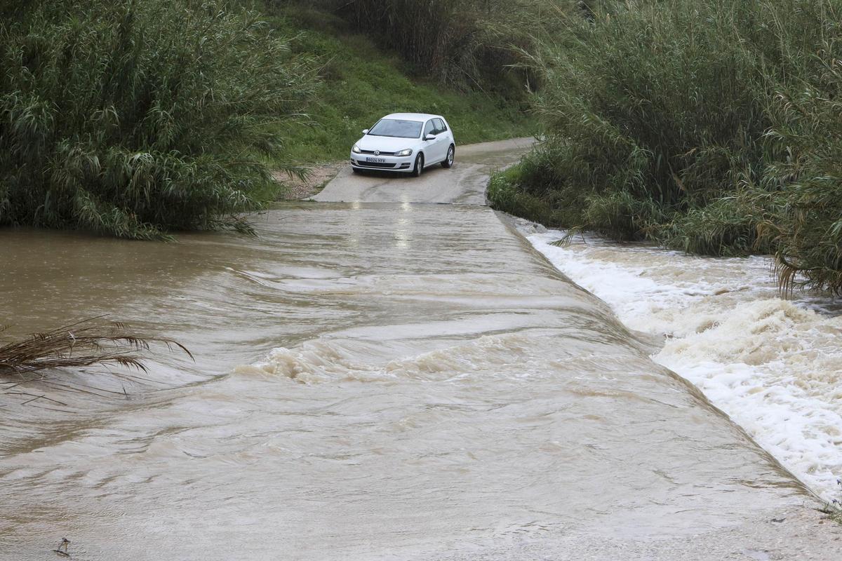 Un coche parado ante un camino de Xàtiva inundado por un temporal.