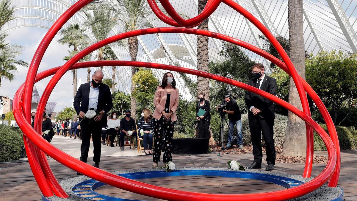 El president de la Generalitat, Ximo Puig, la médica, Esperanza Merino, y el periodista, Luis Motes, depositan flores en la escultura inaugurada durante el acto institucional en memoria de los fallecidos con el que la Generalitat homenajea a las víctimas de la covid-19.