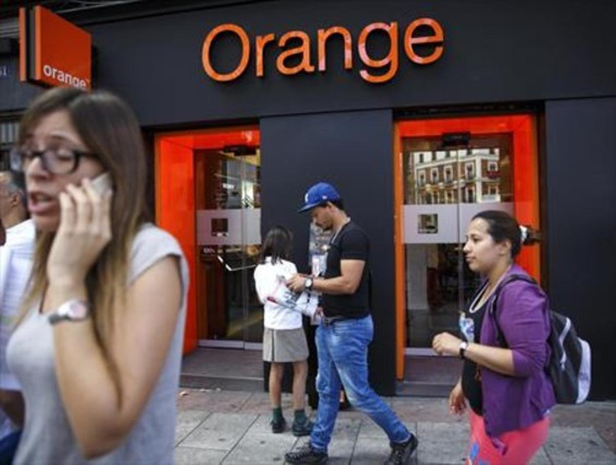 Persones passen per davant d’una botiga d’Orange a Madrid, ahir.