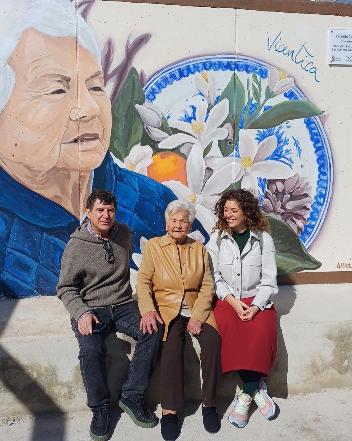 Vicenta Torres Martí posa ante su mural junto a su hijo y la autora de la obra