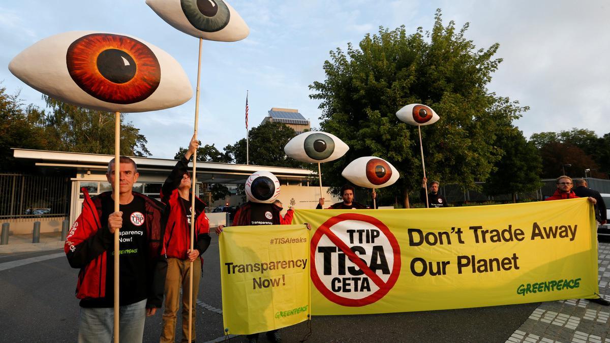 Greenpeace activists hold banners and giant eyes during a demonstration against the trade agreements TTIP, CETA and TiSA in front of the U.S. Mission in Geneva