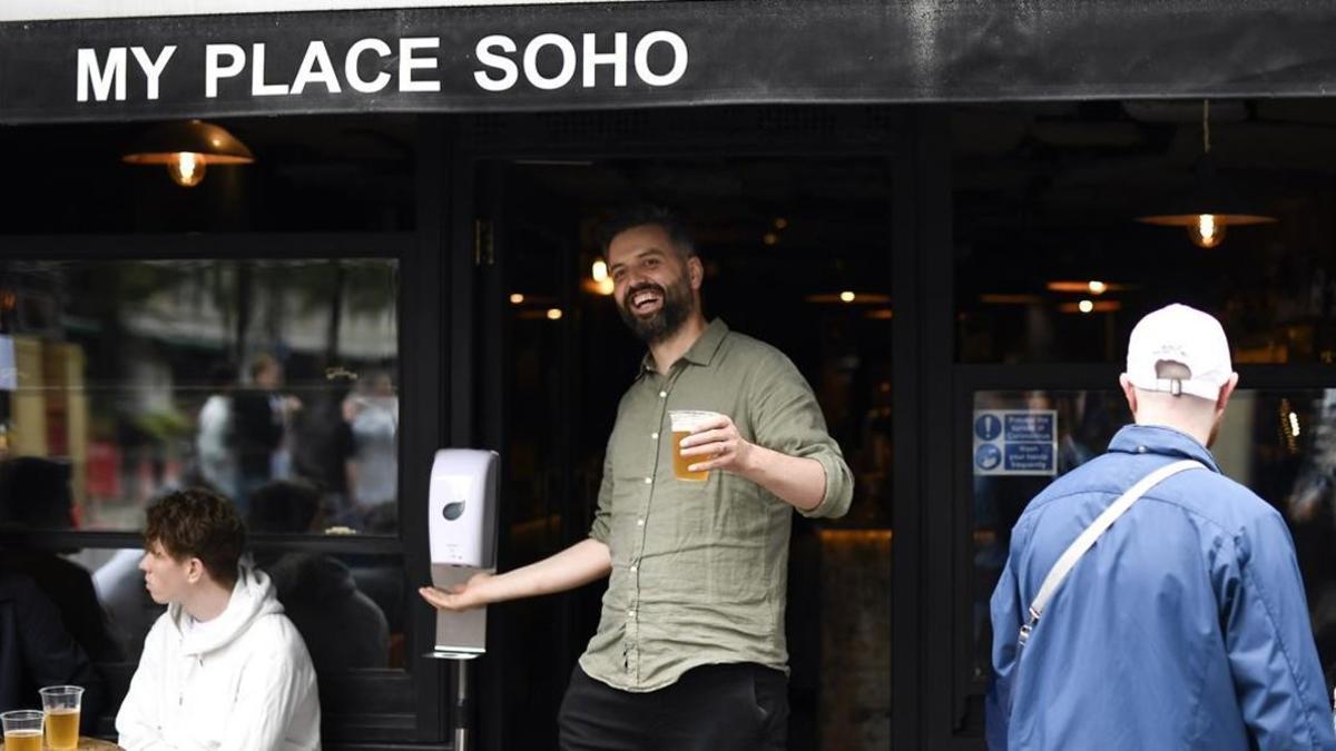 Un hombre con una pinta de cerveza en la puerta de un bar del Soho.