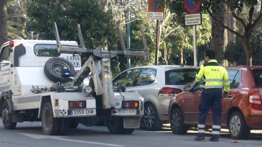 Una grúa municipal retira un vehículo de las calles de Málaga capital.