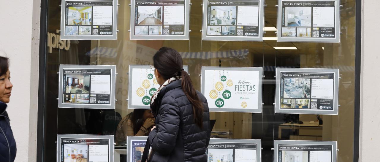 Una mujer mira el escaparate de una inmobiliaria, en una imagen de archivo.