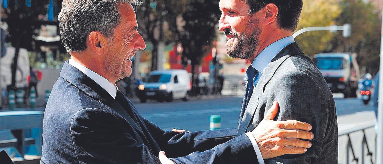 Casado, sonriente junto a Nicolas Sarkozy, antes de conversar en la convención del PP en Madrid.