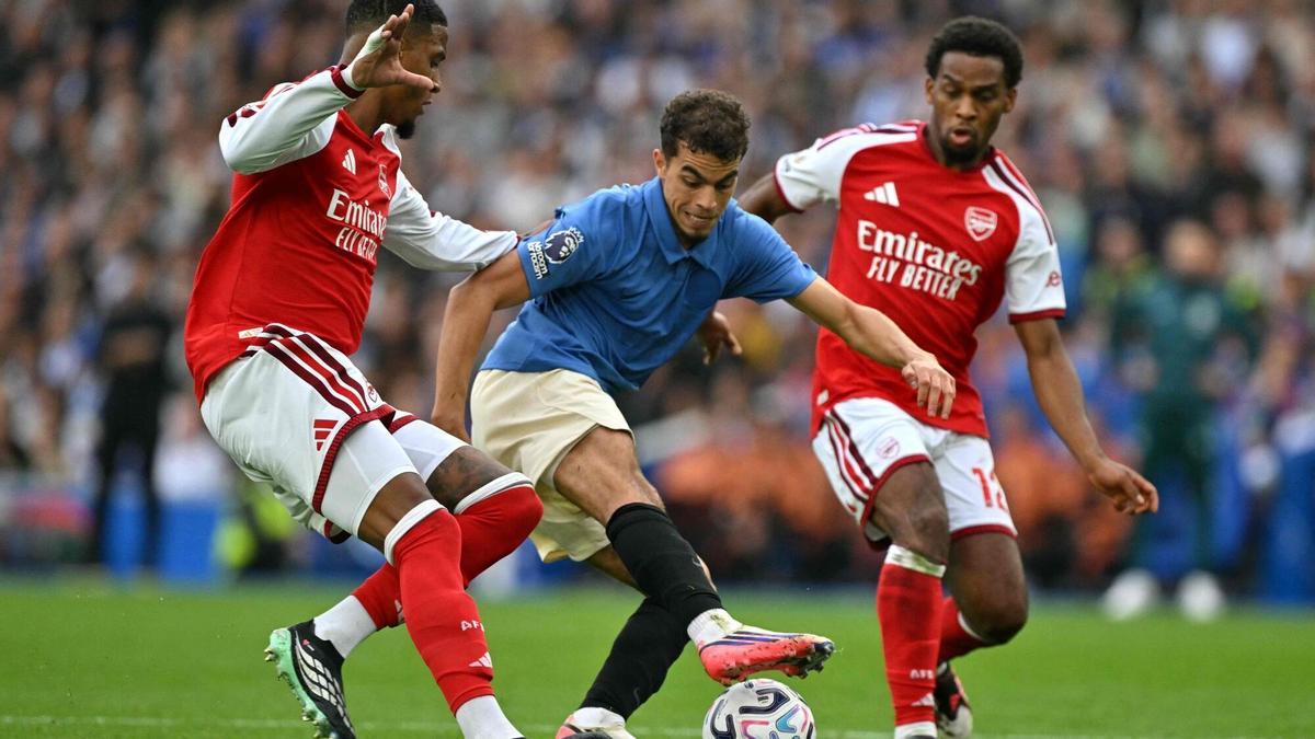 Ayari, del Brighton, controla un balón entre dos jugadores del Arsenal.