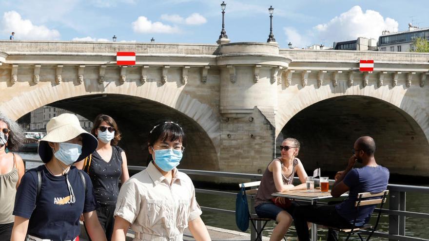 Varias personas con mascarilla caminan por la orilla del Sena.