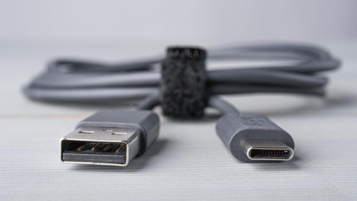 USB Type C and A connector with a grey cable on a wooden background. Closeup with shallow depth of field. Copy space on the bottom.   USB-C   cable telefono
