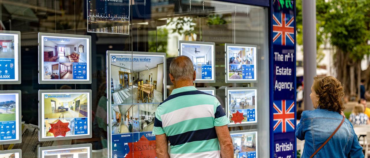 Una pareja observa viviendas a la venta en una inmobiliaria para británicos en Benidomr