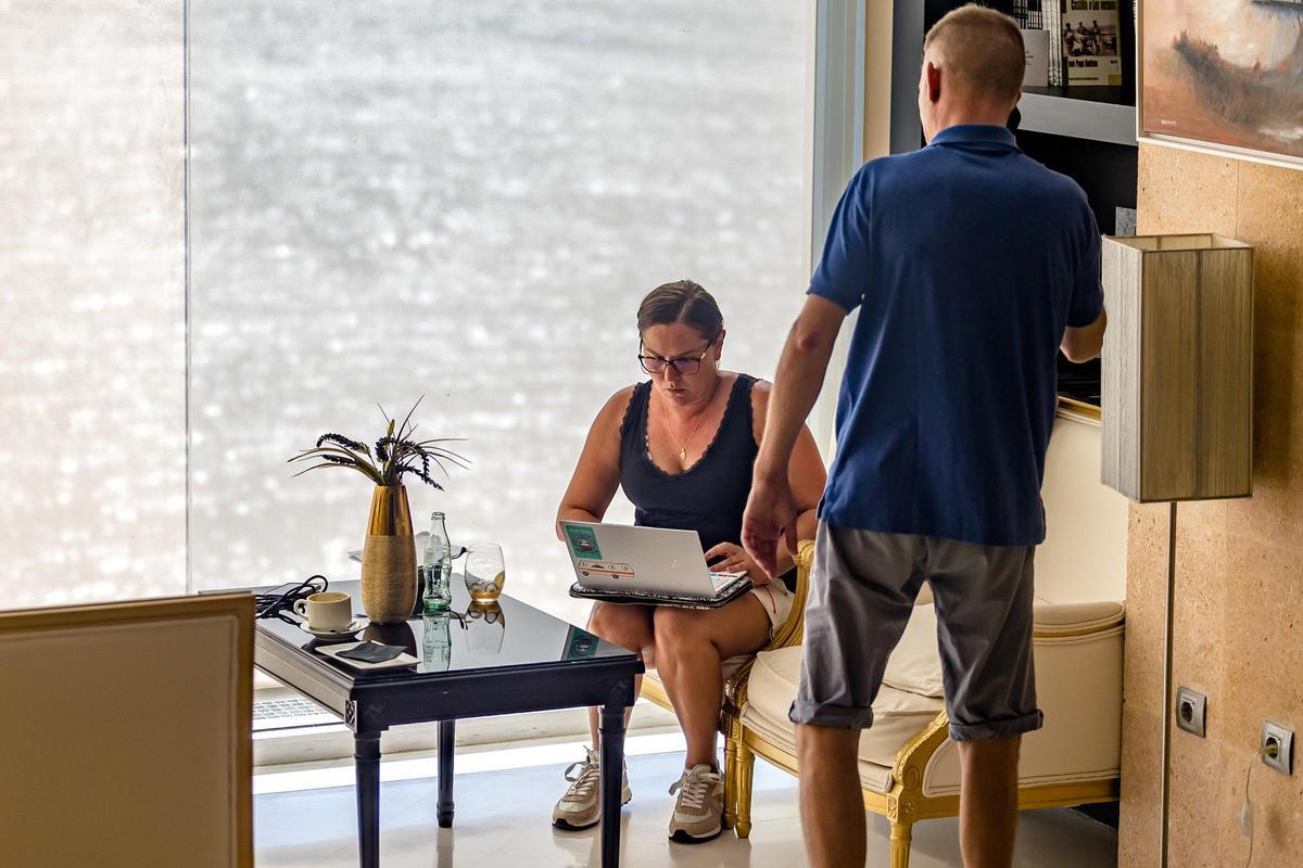 Dos turista en la recepción de un hotel de Benidorm con un ordenador.