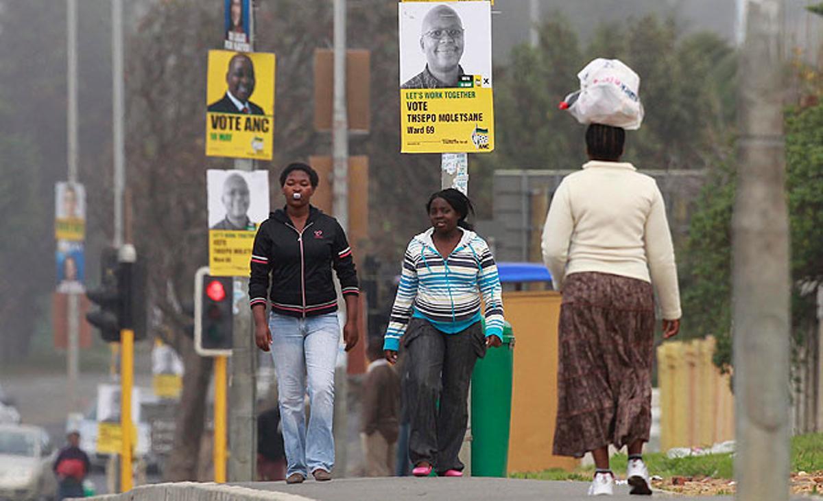 Unes dones caminen aquest diumenge per un carrer de Ciutat del Cap (Sud-àfrica) ple de cartells electorals. Dimecres que ve, 18 de maig, Sud-àfrica celebra eleccions municipals.